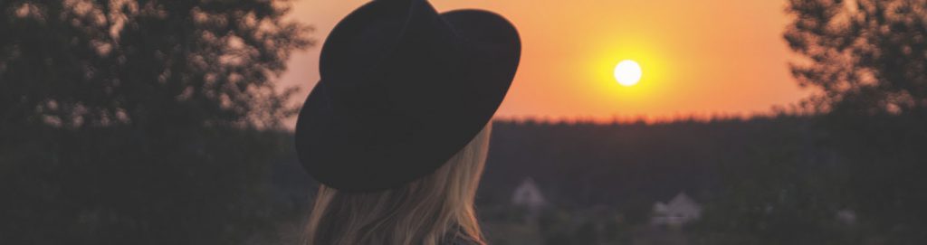 Ung kvinna i hatt som tittar mot horisonten